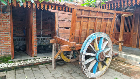 Classic wheeled wooden cart in front of red brick buildingの写真素材
