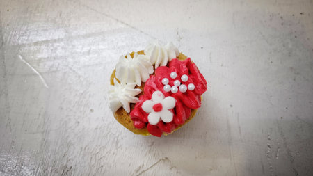 High Angle View of Sweet Cupcake with red and white cream topping and candy sprinklesの写真素材
