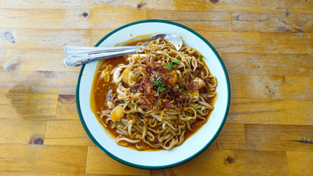 Delicious stir-fried noodles with various seafood side dishes and a sprinkling of fried onionsの写真素材