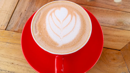 Coffee with latte art decoration in a red cupの写真素材