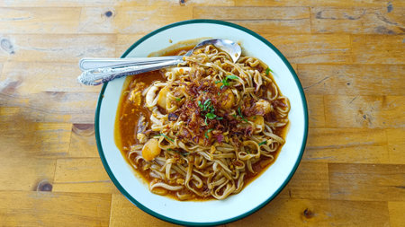 Delicious stir-fried noodles with various seafood side dishes and a sprinkling of fried onionsの写真素材