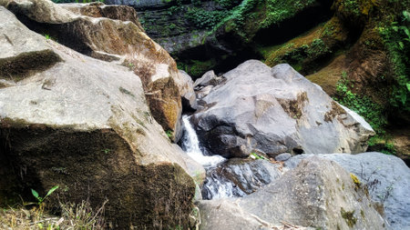Fresh of water from a natural spring flowing between big rocksの写真素材