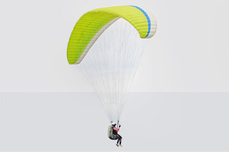 paragliding pilot flying in the blue sky with white cloudsの写真素材