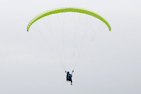 paragliding pilot flying in the blue sky with white cloudsの写真素材