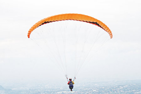 paragliding pilot flying in the blue sky with white cloudsの写真素材