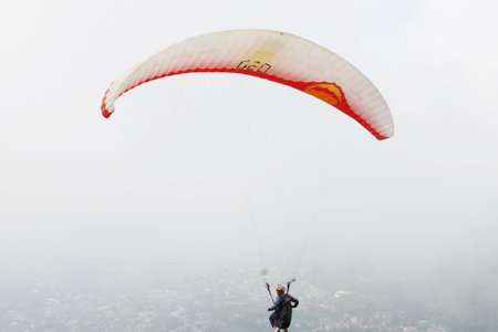 paragliding pilot flying in the blue sky with white cloudsの写真素材