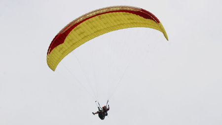 paragliding pilot flying in the blue sky with white cloudsの写真素材