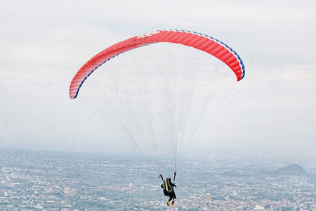 Paraglider flying high above village view and blue sky backgroundの写真素材