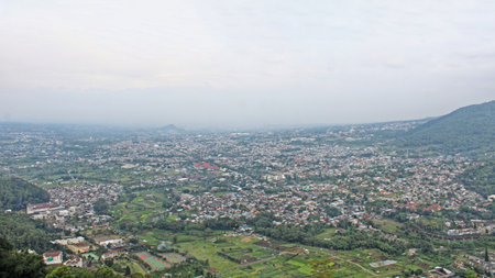 beautiful village view at the foot of mountains and hills with blue sky and white cloudsの写真素材
