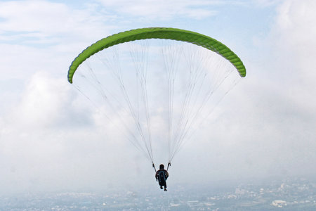 paragliding pilot flying in the blue sky with white cloudsの写真素材