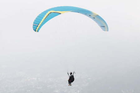 paragliding pilot flying in the blue sky with white cloudsの写真素材