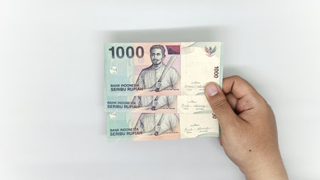 hand holding old Indonesian banknotes in the 1000 rupiah denomination