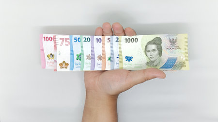hand holding a collection of Indonesian banknotes in denominations 1000, 2000, 5000, 10000, 20000,...