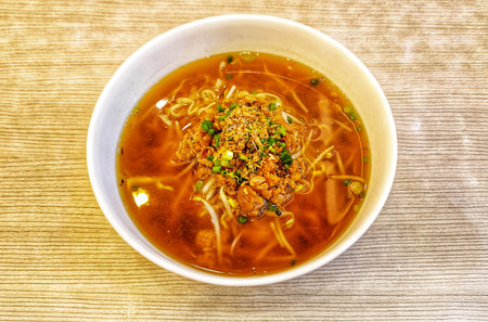 high angle view delicious a bowl of yellow noodles with chicken, various vegetables and broth