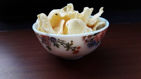 rice onion chips in bowl isolated on brown background