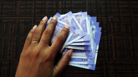 indian currency cover with hand isolated on brown background