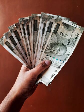 indian note in hand isolated on brown backgroundの写真素材