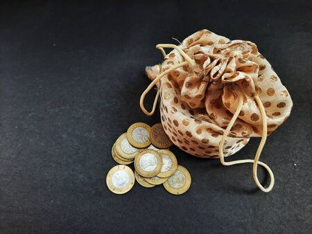 indian coins with pouch isolated on black background