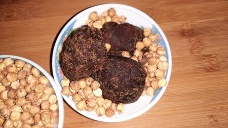 roasted black grams and jaggery in bowl isolated on wooden background