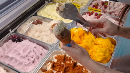Close up of female hands scooping ice cream from a container in a supermarket.
