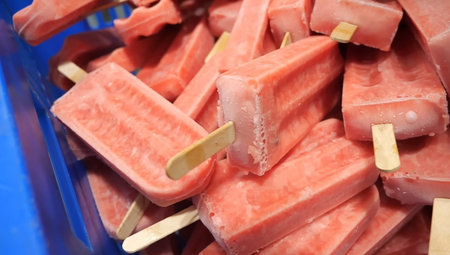 Frozen pink watermelon popsicles on a stick in a supermarket