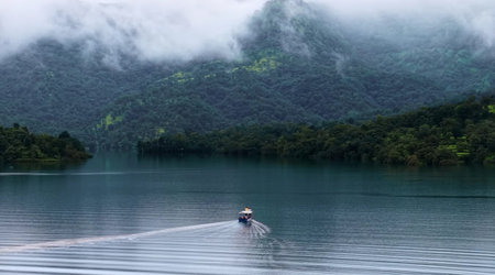 Boat on the lake in the foggy morning with mountain backgroundの写真素材
