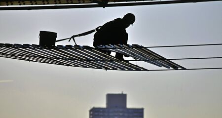 a city worker suspended in the air as he repairs parts of a highway