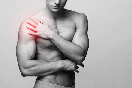 Studio shot of a young muscular man with pain problemsの写真素材
