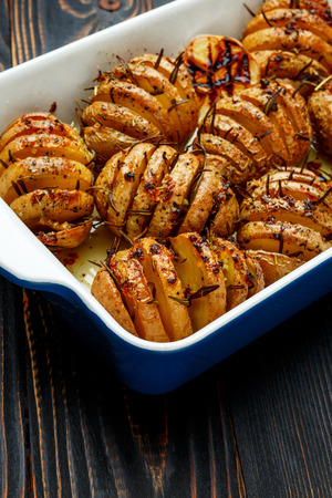 Baked spicy potatoes in baking dish closeup