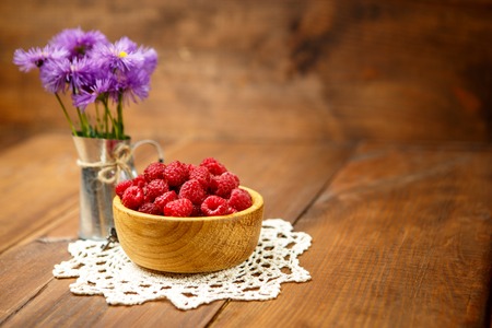 Studio shot of fresh natural raspberries on wooden background