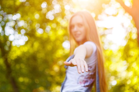 Portrait of beautiful caucasian smiling red-haired young woman, against summer green park.の写真素材
