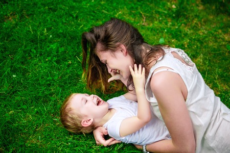 Cute cheerful child with mother play outdoors in parkの写真素材