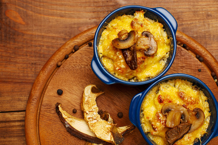 Moshroom casserole in a blue ceramic pot on wooden tableの写真素材