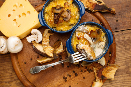 Moshroom casserole in a blue ceramic pot on wooden tableの写真素材
