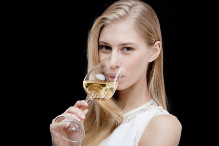 young blond woman holding glass of white wineの写真素材