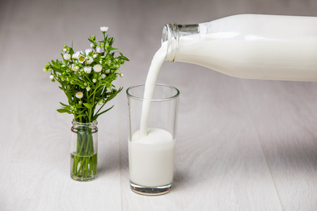 milk bottle and glass, wildflowers on wooden backgroundの写真素材