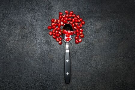 Pomegranate seeds close-up on dark concrete background