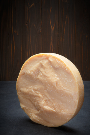 Whole round Head of parmesan or parmigiano hard cheese on concrete backgroundの写真素材