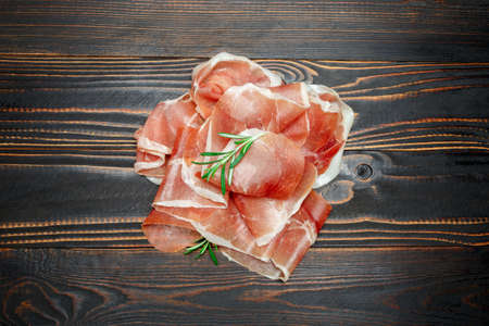 Italian prosciutto crudo or spanish jamon. Raw ham on wooden backgroundの写真素材