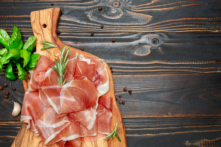 Italian prosciutto crudo or spanish jamon. Raw ham on wooden backgroundの写真素材
