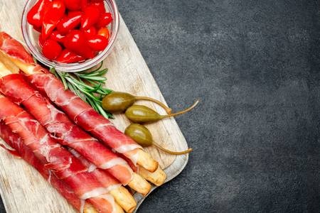 traditional italian snack prosciutto crudo bread sticks, peppers and capersの写真素材