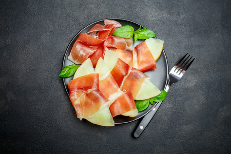 italian food with melon and prosciutto on the plateの写真素材