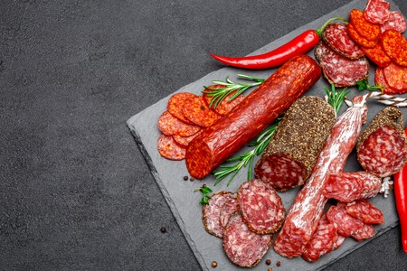 Various types of Dried organic salami sausage on stone serving boardの写真素材