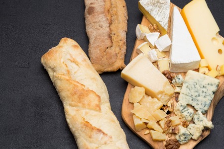 various types of cheese and bread on wooden board