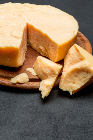 Whole round Head and pieces of parmesan or parmigianoの写真素材