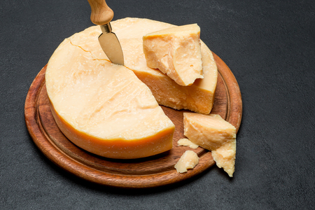 Whole round Head and pieces of parmesan or parmigianoの写真素材
