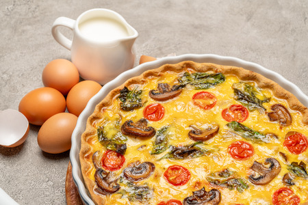 Baked homemade quiche pie in ceramic baking form, eggs and creamの写真素材