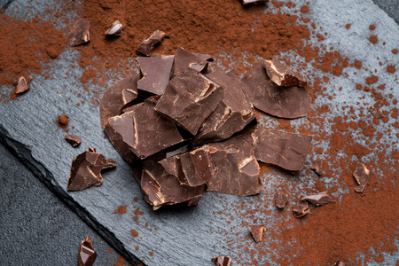 Dark or milk organic chocolate pieces on dark concrete backgound