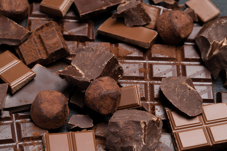 Dark or milk organic chocolate pieces, cocoa powder and truffle candies on dark concrete backgoundの写真素材