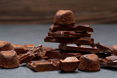 Dark or milk organic chocolate pieces, cocoa powder and truffle candies on dark concrete backgound